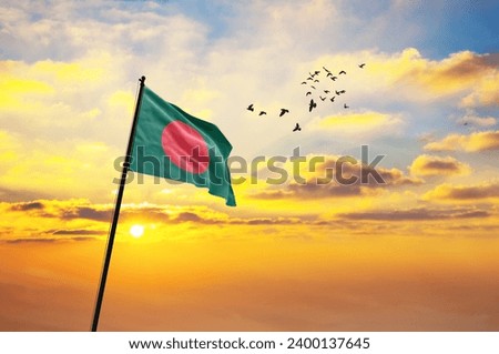 Waving flag of Bangladesh against the background of a sunset or sunrise. Bangladesh flag for Independence Day. The symbol of the state on wavy fabric.