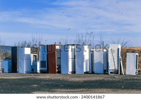 Old refrigerators and freezers at a scrapyard for recycling Royalty-Free Stock Photo #2400141867