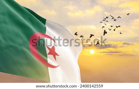 Waving flag of Algeria against the background of a sunset or sunrise. Algeria flag for Independence Day. The symbol of the state on wavy fabric.