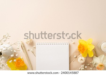 Embrace essence of spring season with daffodils and gypsophila. Above view photo features flower and petals and envelope on beige isolated background with blank notepad page inviting adverts or text