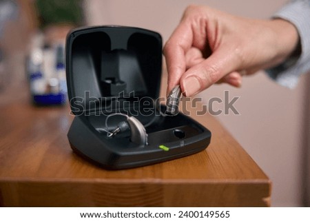 Close Up Of Person Picking Up Wireless Hearing Aid Or Device From Charging Case At Home Royalty-Free Stock Photo #2400149565