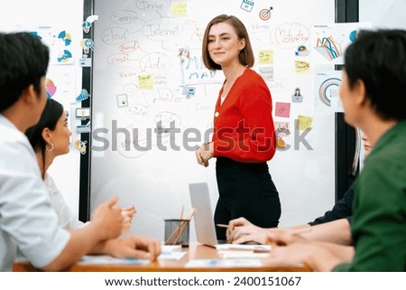 Professional attractive female leader presents creative marketing plan by using brainstorming mind mapping statistic graph and colorful sticky note at modern business meeting room. Immaculate. Royalty-Free Stock Photo #2400151067
