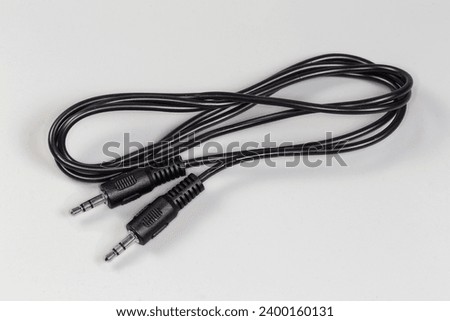 Rolled up black analog audio cable with stereo connectors mini jack on the edges lies on a gray surface close-up 
 Royalty-Free Stock Photo #2400160131