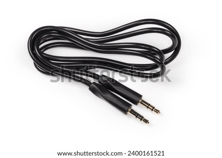 Rolled up black analog audio cable with gold-plated stereo connectors mini jack on the edges lies on a white surface close-up 
 Royalty-Free Stock Photo #2400161521