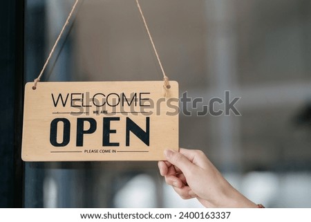 Owner of the cafe stands at the door with a sign Open waiting for customers. Small business concept, cafes and restaurants.