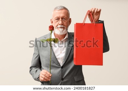 Mature man with rose flower and shopping bag on white background. Valentine's day celebration Royalty-Free Stock Photo #2400181827