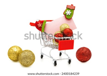 Blank greeting card with wooden decorative clothespins and Christmas tree toys in supermarket grocery shopping cart isolated on white background. Christmas, New Year, St. Nicholas Day. Winter holiday.