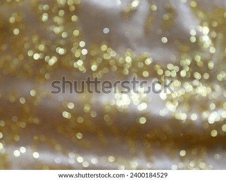 Defocused, Blurred, Bokeh, and Out of Focus Gold Lights From A Sparkling Silky Fabric, Moving Light Abstract for Background and Celebration Pusposes