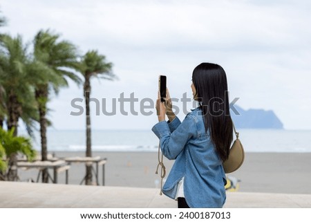 Woman use mobile phone to take photo in Yilan sand beach at Taiwan