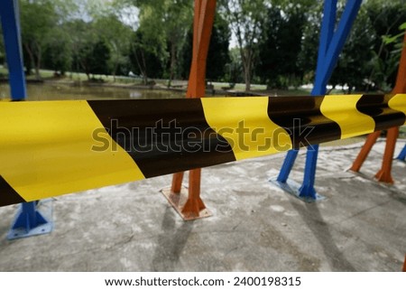 ribbon or barricade with black yellow stripes with defocused lake background. concept illustration of a person drowning in a lake