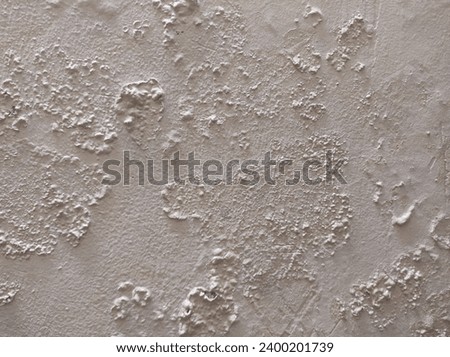 Abstract Rough Dry paint is peeling off the building wall.Close-up. Badly fixed building facade wall covered with cracks in stucco and paint. Missing patch of paint in the middle; crack with flappy. Royalty-Free Stock Photo #2400201739
