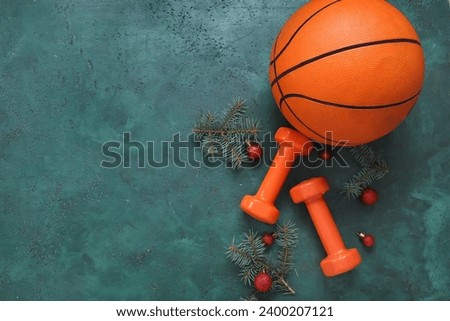 Composition with basketball ball, dumbbells and Christmas tree branches on green background
