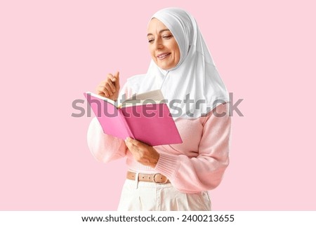 Mature Muslim woman with notebook on pink background