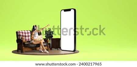Young woman in headphones sitting on couch near giant 3D model of mobile phone with empty screen over green background. Online services, business, e-commerce. Mockup for text, ad, design, logo