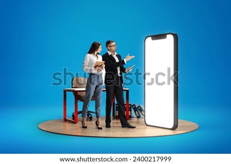 Business project presentation. Businessman pointing at big 3D model of phone with empty over blue background. Online app development. Web designer, IT. Mockup for text, ad, design, logo