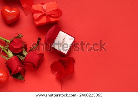 Beautiful composition with engagement ring and rose flowers on red background. Valentine's day celebration