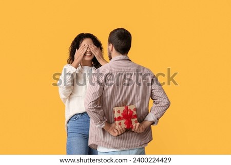 Man greeting his girlfriend with Valentine's day on yellow background Royalty-Free Stock Photo #2400224429