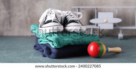 Stack of baby clothes, booties and toys on grunge background