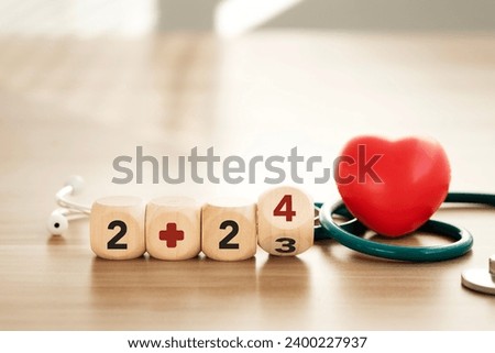 Happy New Year 2024, stay healthy, family insurance, health insurance. Image consists of a wooden block with the word 2024 and a stethoscope with a red heart. There is a field to enter text.