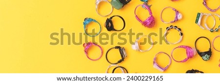 Banner with rings made of wire and natural stones scattered on a yellow background. 