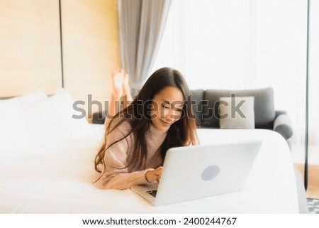 Portrait beautiful young asian woman using laptop for working on bed in bedroom interior