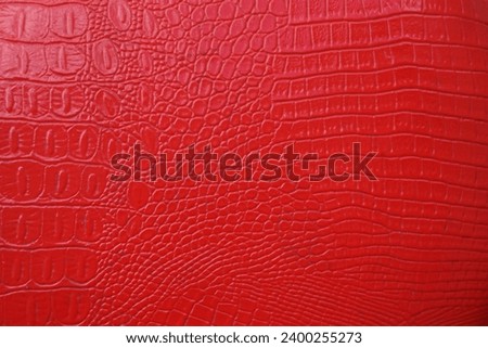 red crocodile skin artificial leather with waves and folds on PVC base. mock up space. empty background of Red crocodile leather. mockup texture backdrop. top view image. Royalty-Free Stock Photo #2400255273