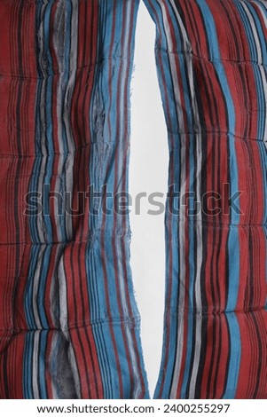 teared rag spread isolated on white background, can use like a backdrop or any texture. big hole in the tissue. striped beige cotton fabric with torn stitch, hole and loose threads. mattress