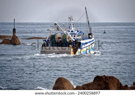 Trawler leaving the port of Barfleur, a commune in the peninsula of Cotentin in the Manche department in Lower Normandy in north-western France Royalty-Free Stock Photo #2400258897