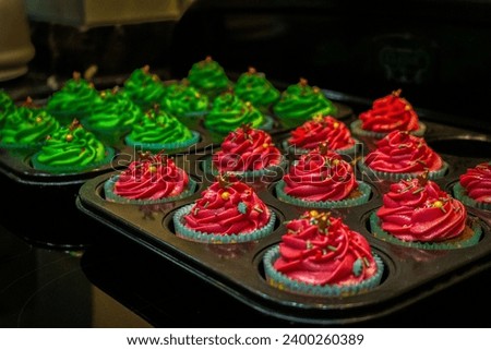 Freshly decorated Christmas cupcakes one batch of green and the other pink
