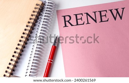 RENEW word on pink paper with office tools on white background