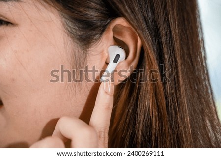 Close up of Happy female touching earbuds to control next listen song on mobile phone in living room at home, Lifestyle woman wearing wireless earphones listening to favorite song on her smartphone Royalty-Free Stock Photo #2400269111