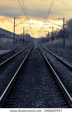Perspective view of railroad tracks, at sunset, with a blueish and cinematic color grading Royalty-Free Stock Photo #2400269937