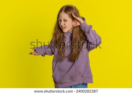 I cant hear you. What. Child girl kid trying hear you, looking confused and frowning, keeping arm near ear for louder voice asking to repeat to hear information deafness. Children on yellow background Royalty-Free Stock Photo #2400282387