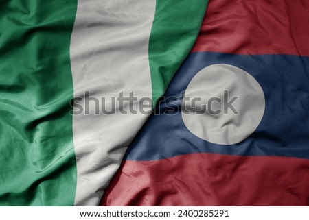 big waving national colorful flag of laos and national flag of nigeria . macro