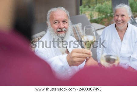Senior couple in white bathrobes receiving champagne from a waiter in a spa hotel. Birthday and Valentines day concept image