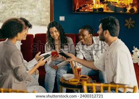 Happy group of friends sharing each other photos they made on phone on holiday party at home