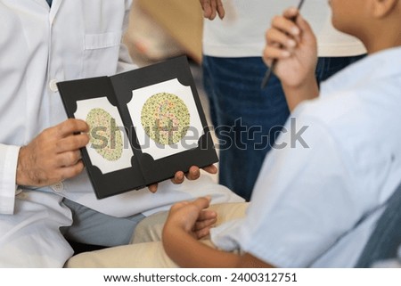 Optometrist doing color blindness disease perception test in optical shop, Boy doing eye test checking examination with optometrist in optics store Royalty-Free Stock Photo #2400312751