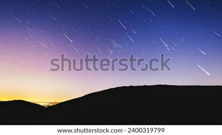 The image captures a beautiful night sky with a hill in the foreground. The sky is filled with a multitude of stars, creating a stunning backdrop for 