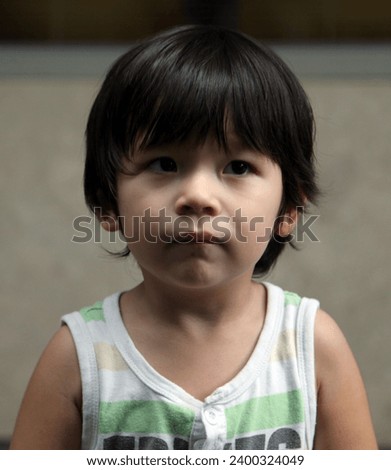 Exterior close up photo portrait of a cute handsome good looking adorable young kid child male boy who  has a neutral expression and pretty face head shot in an outdoor location during the day
