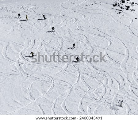 Snowboarders and skiers downhill on snowy off piste slope. High winter mountains. Top view. 