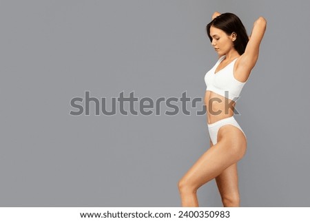 Profile of calm asian millennial woman in white underwear, show healthy figure and strength, enjoy body care, weight loss, isolated on grey background. Health and fit lifestyle Royalty-Free Stock Photo #2400350983