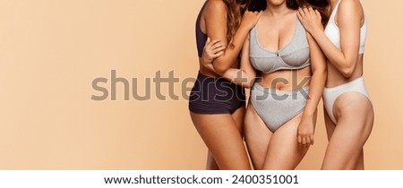 Three diverse young women in comfortable undergarments with different types figure enjoy spare time in light background, panorama. Support, friendship and fashion, love to yourself Royalty-Free Stock Photo #2400351001