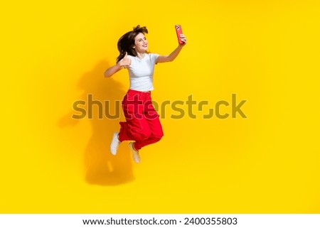 Full length photo of sweet cool lady wear white t-shirt jumping vlogging video recording modern device thumb up isolated yellow color background