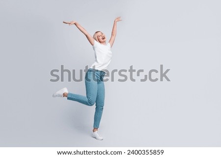 Full length photo of good mood cute girl dressed white t-shirt denim pants rasing hands up like wings isolated on gray color background Royalty-Free Stock Photo #2400355859