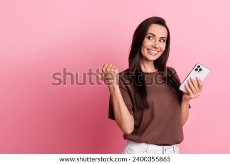 Portrait of young cheerful brunette hair business woman directing finger empty space betting program isolated on pink color background