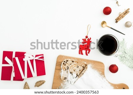 Christmas table with tasty stollen cake, coffee cup, tree toys and gift boxes on white. Flat lay, top view.