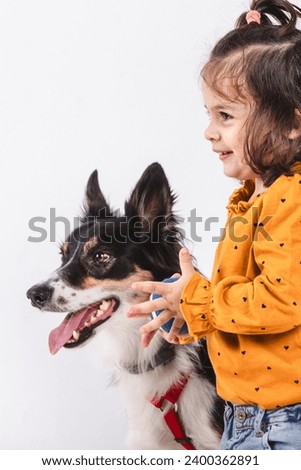 Profile of a smiling little girl with a border collie dog on white background