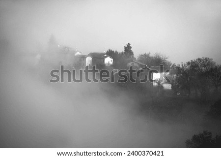 View of the foggy village in the mountains. Black and white.