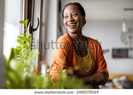 Portrait of a smiling mature woman standing in her apartment Royalty-Free Stock Photo #2400370569