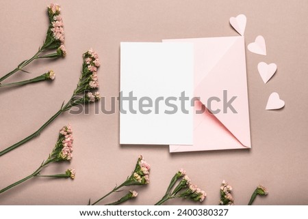 Pink envelope and blank form, pink flowers on a brownish background. Paper pink hearts. Concept for Valentine's Day, Mother's Day.
